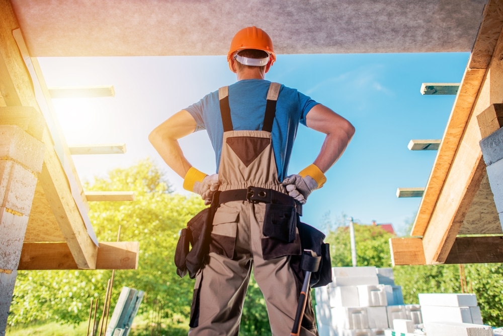 Home builder in a power pose looking out from a new construction house