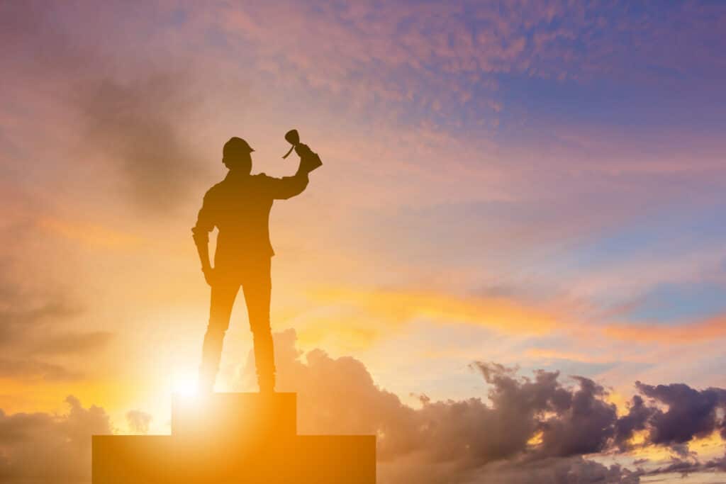 Silhouette of builder holding a certification up to the sky